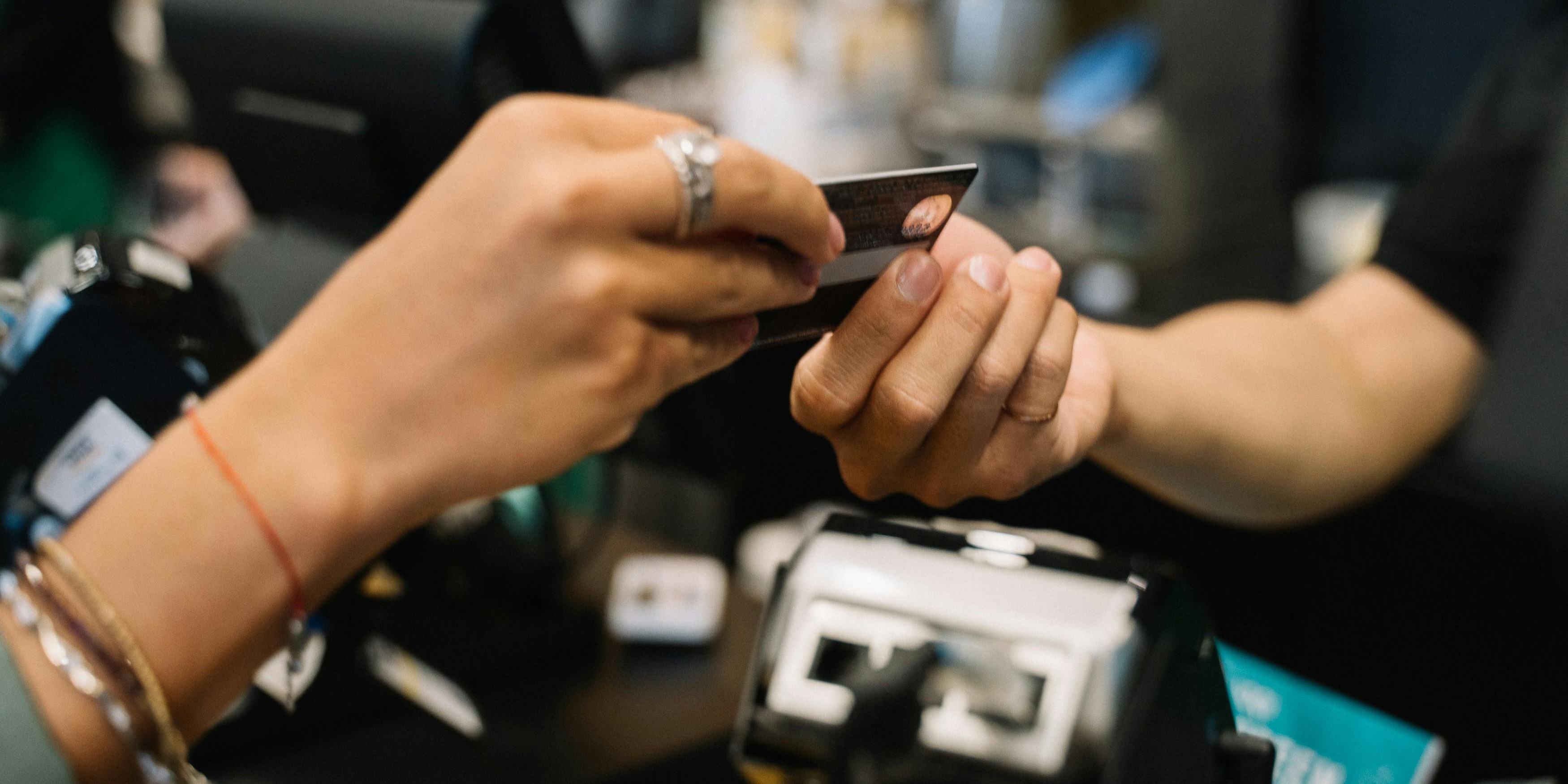 a credit card is handed between a customer and a cashier at a cash register