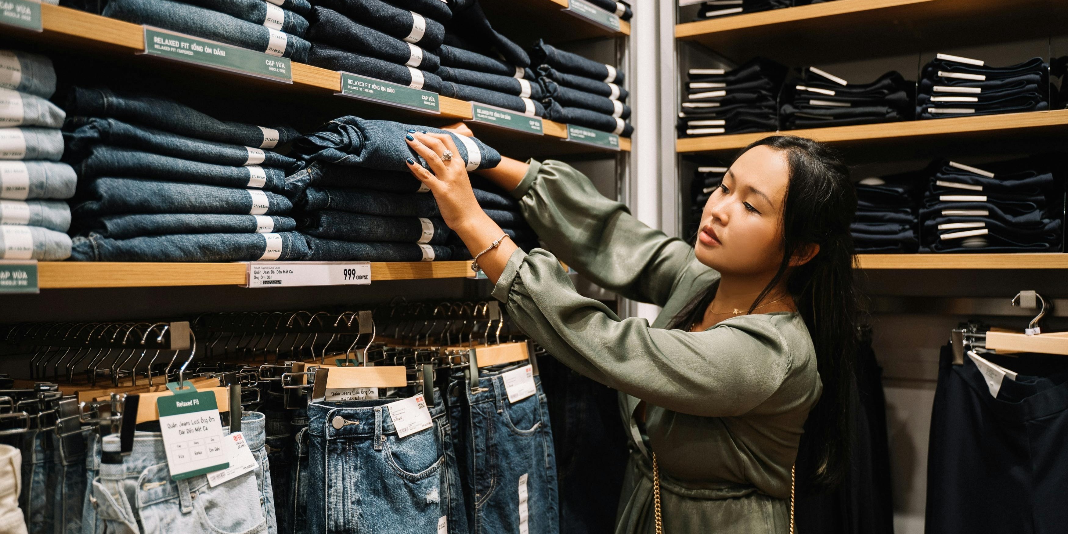 A young woman browses jeans in a clothing store