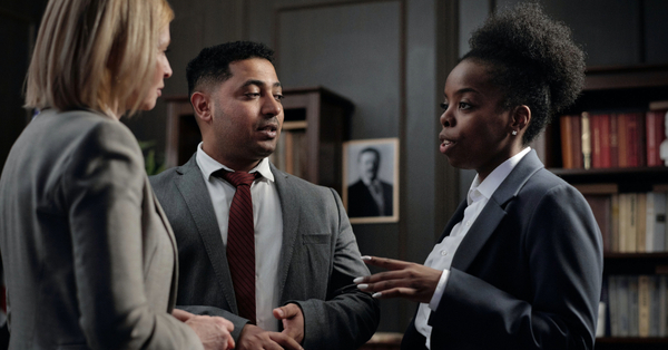 A group of lawyers is engaged in terse discussion.