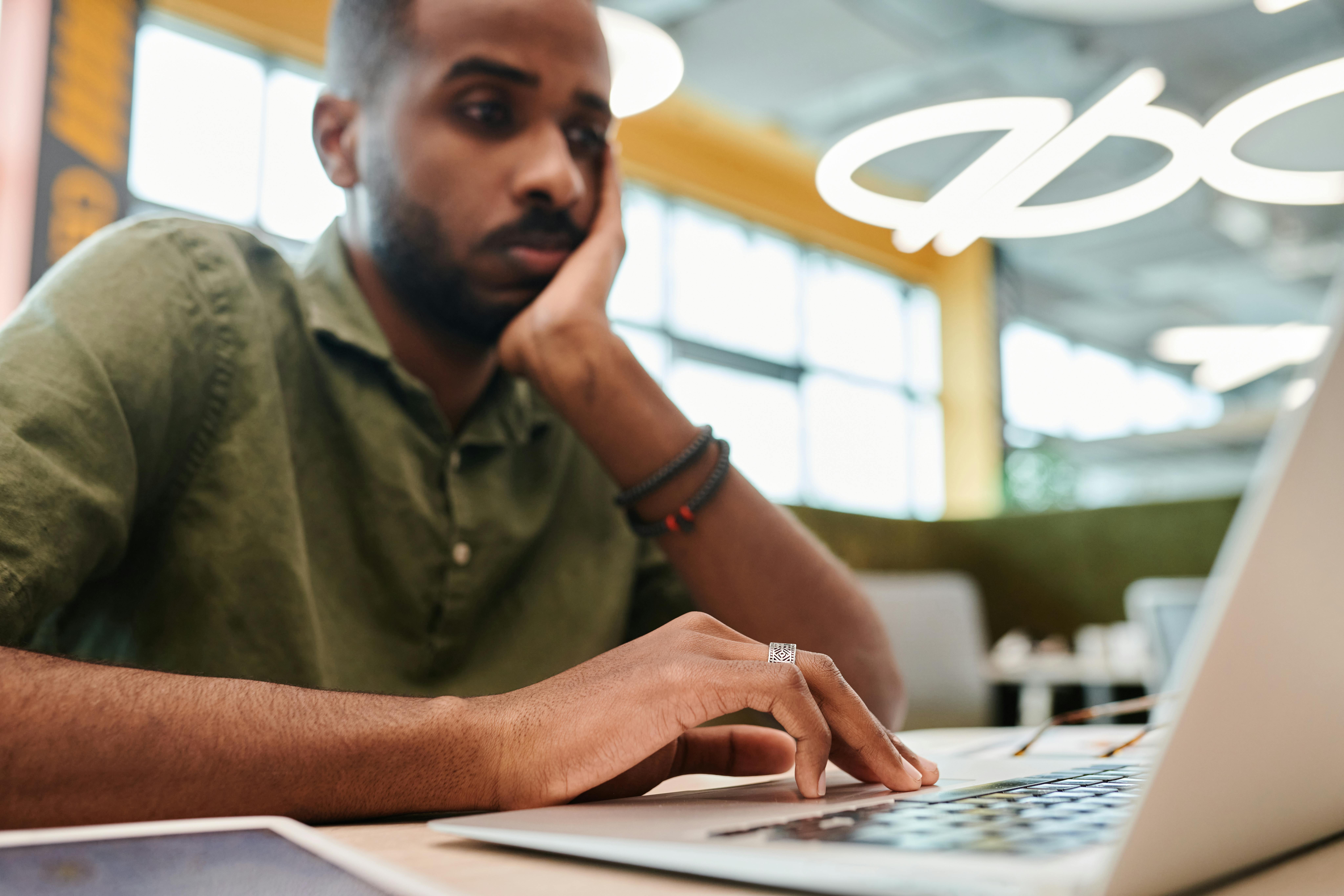 a man seems frustrated looking at his laptop